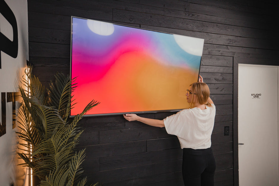 Understanding TV Dimensions: How Do You Measure A TV? woman fixing a mounted tv