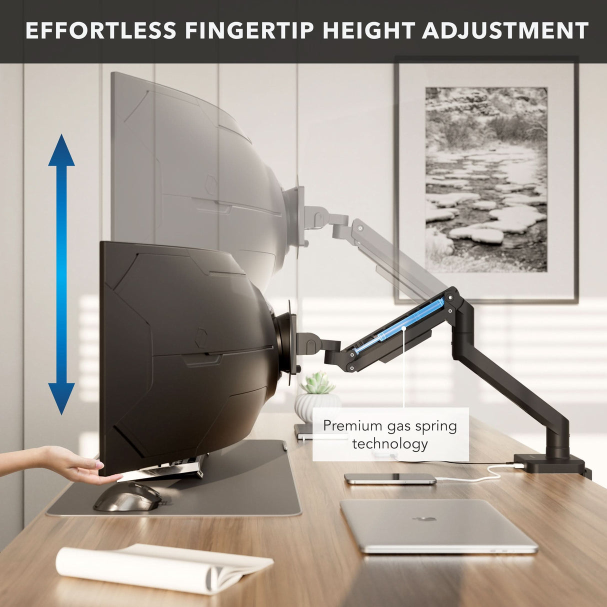 Heavy-Duty Monitor Mount with Gas Spring Arm A hand adjusts the Mount-It! Heavy-Duty Monitor Mount with Gas Spring Arm, showing easy fingertip height adjustment and built-in cable management. The workspace also features a laptop, phone, and notebook.