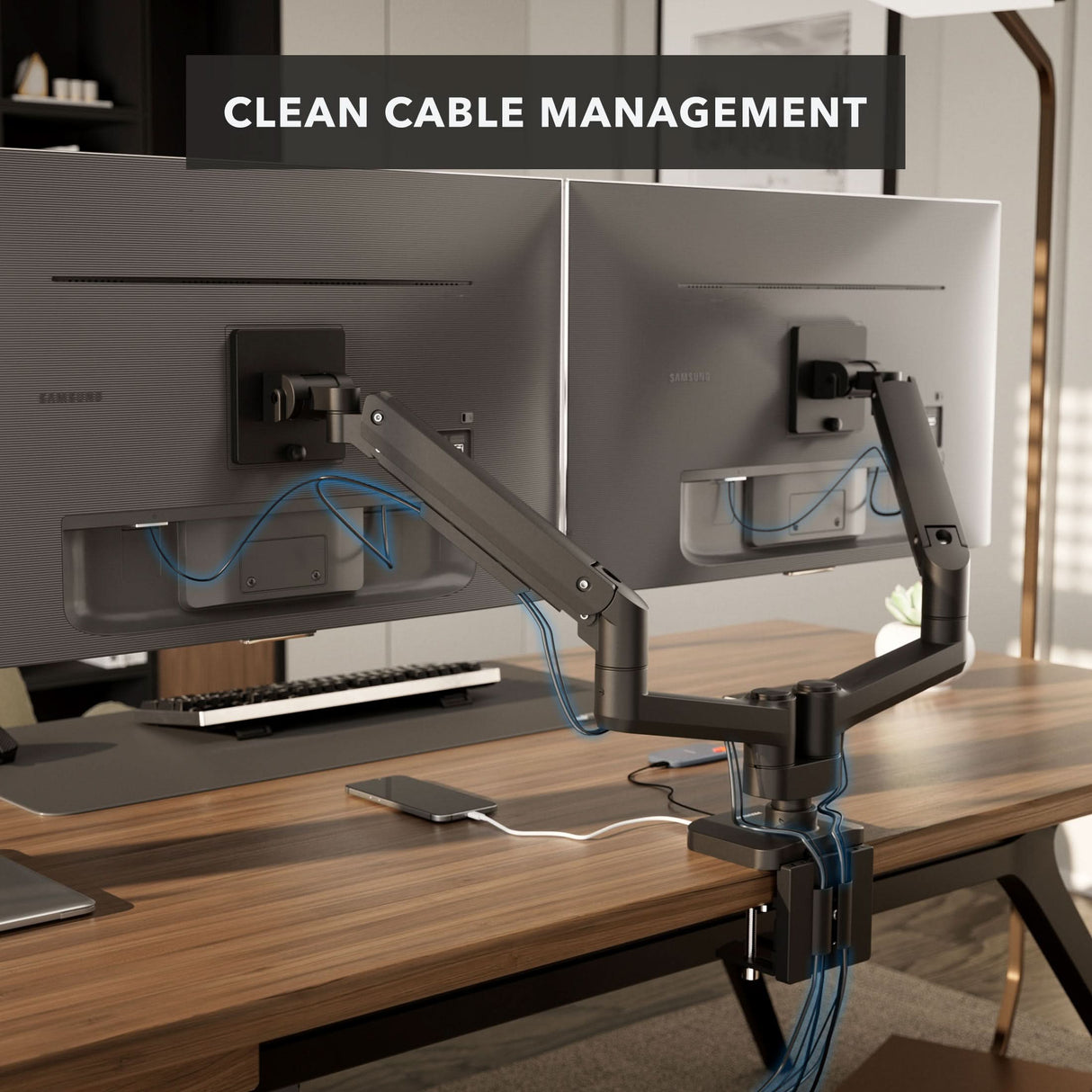 Heavy-Duty Dual Monitor Mount with Gas Spring Arms Two monitors mounted on the Mount-It! Heavy-Duty Dual Monitor Mount with Gas Spring Arms, featuring organized cables and set on an ergonomic desk with a keyboard, mouse, and notepad. Text overlay: “CLEAN CABLE MANAGEMENT.”.