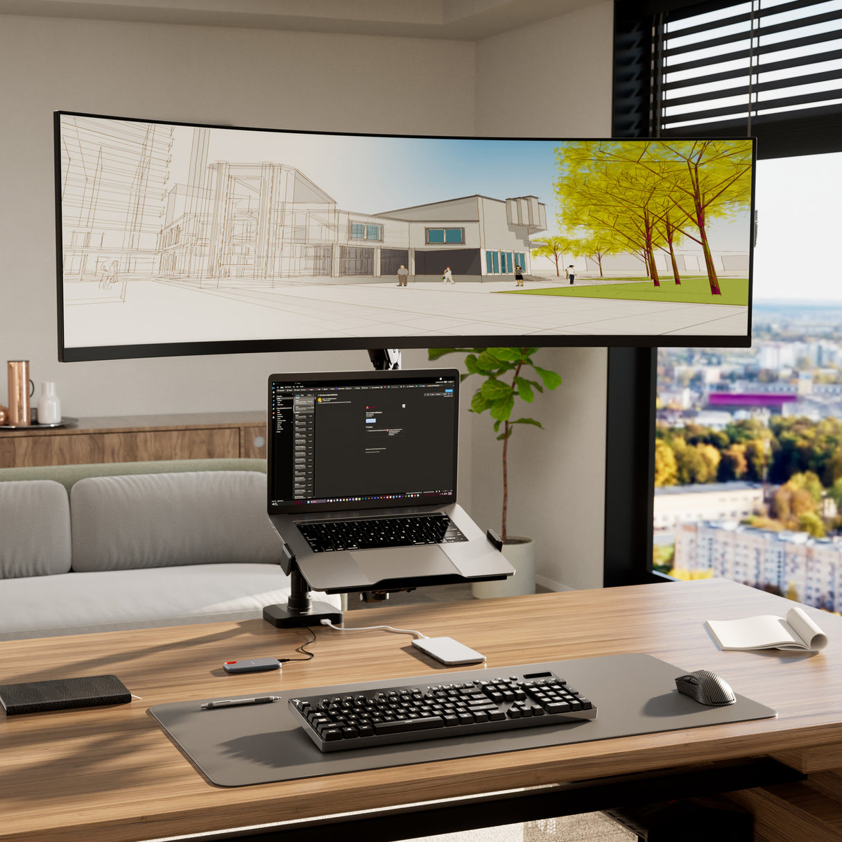 A modern office desk features a Mount-It! Heavy-Duty Monitor and Laptop Mount with Pole and Gas Spring Arms holding a curved ultrawide monitor (showing an architectural rendering) and laptop (with chat app), plus wireless keyboard, mouse, and city views outside large windows.