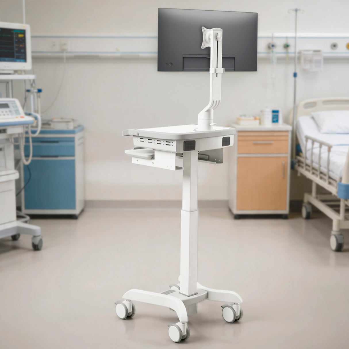 The Mount-It! MedHub Swivel Monitor Mount, a medical computer workstation on wheels with a monitor and adjustable arm, is placed in a hospital room beside a bed and medical equipment.