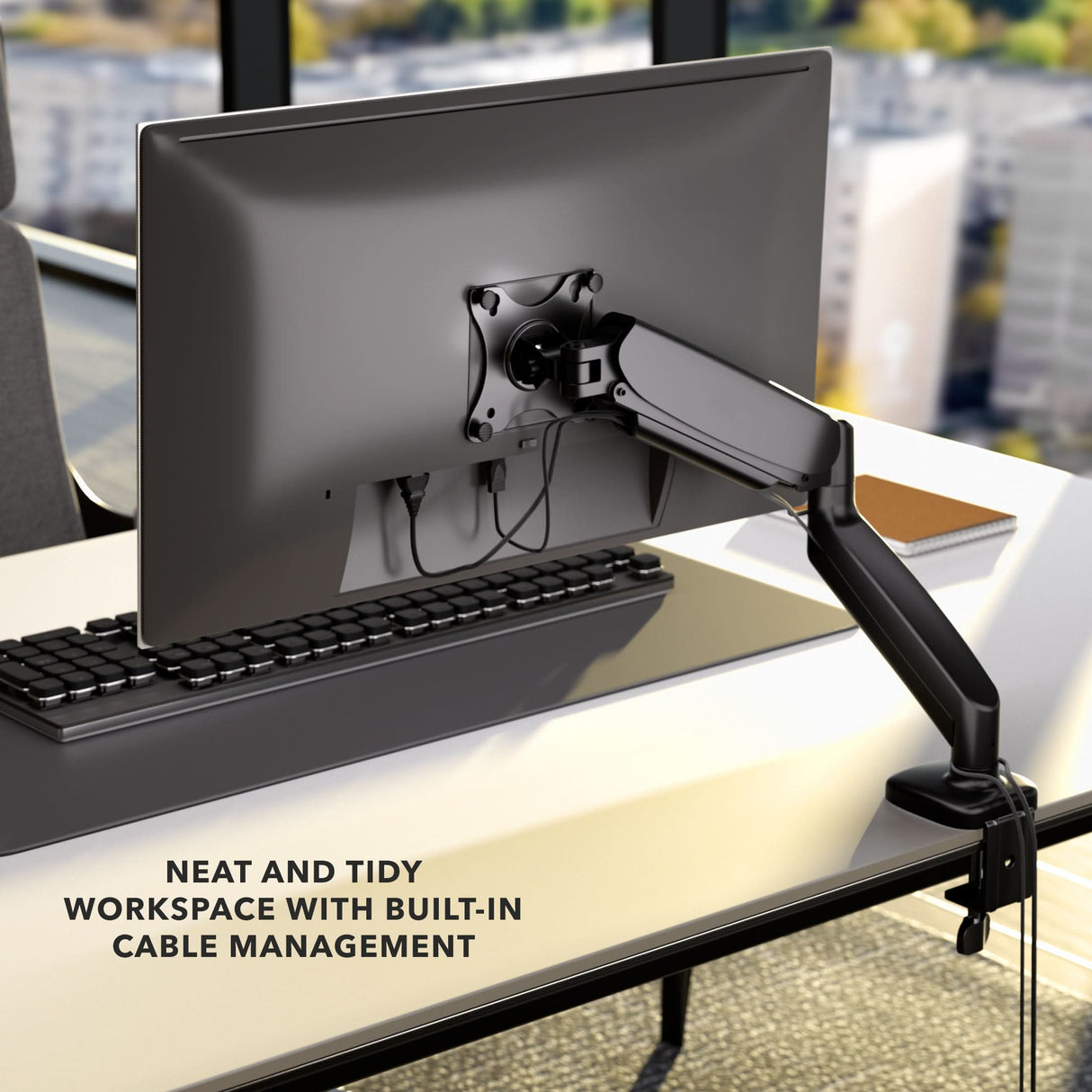 Single Monitor Desk Mount with Gas Spring Arm A Mount-It! Single Monitor Desk Mount with Gas Spring Arm and built-in cable management keeps a monitor and keyboard organized on a neat office desk overlooking the city. Text: NEAT AND TIDY WORKSPACE WITH BUILT-IN CABLE MANAGEMENT.