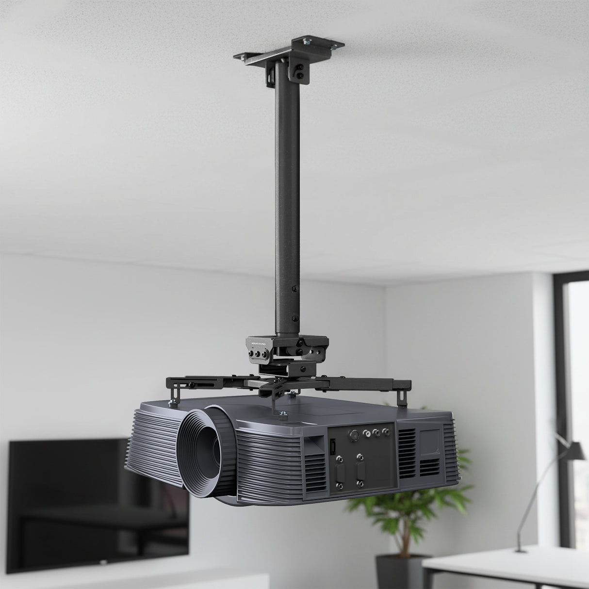 Heavy-Duty Universal Ceiling Projector Mount The Mount-It! Heavy-Duty Universal Ceiling Projector is mounted on an adjustable bracket in a modern, bright room with white walls and a TV in the background.