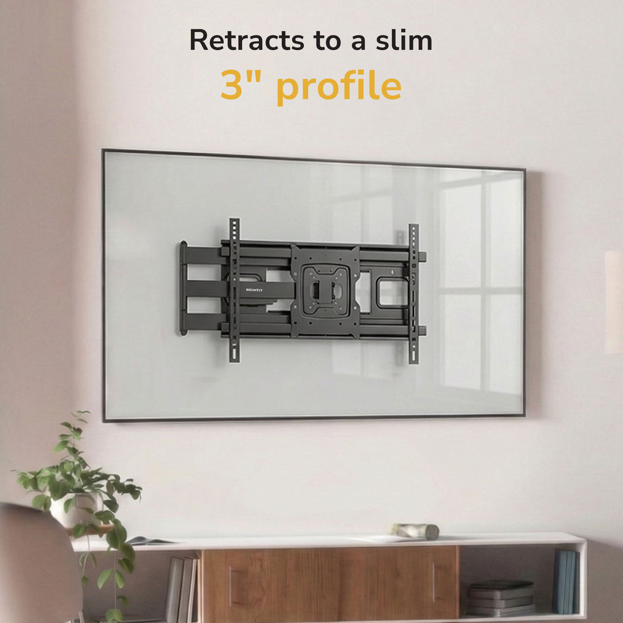 A Mount-It! Full-Motion TV Wall Mount with 40" Extension is installed above a white console on a light wall. Text above says “Retracts to a slim 3" profile” in black and yellow. Features tilt and swivel for perfect viewing.