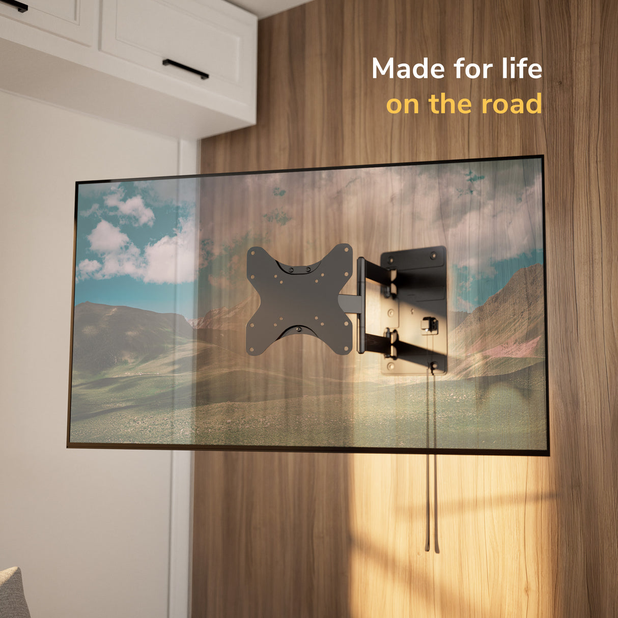 A Mount-It! RV and Trailer TV Wall Mount with Lockable Arm holds a flat-screen TV displaying a scenic landscape. Text in the corner reads, "Made for life on the road." The modern setting feels cozy and inviting.