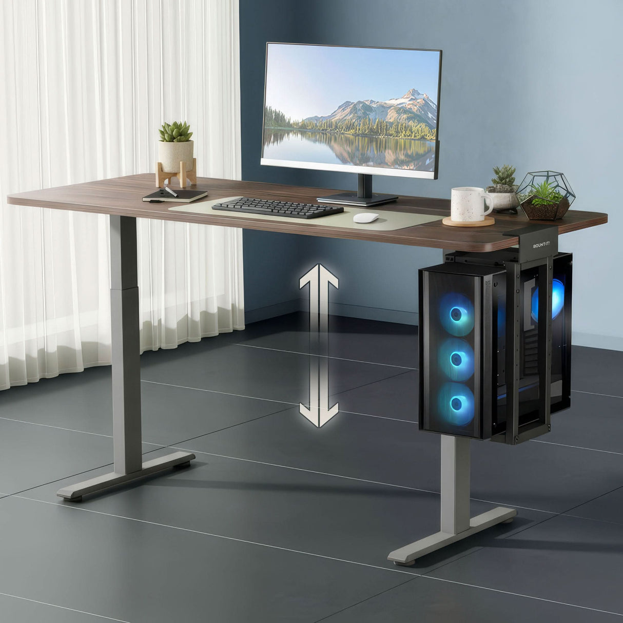 Heavy-Duty Clamp-On CPU Mount A modern office with a height-adjustable desk features a monitor, keyboard, mouse, plant, and a large PC tower secured in the Mount-It! Heavy-Duty Clamp-On CPU Mount with blue fans. An arrow highlights the desk's adjustable height.
