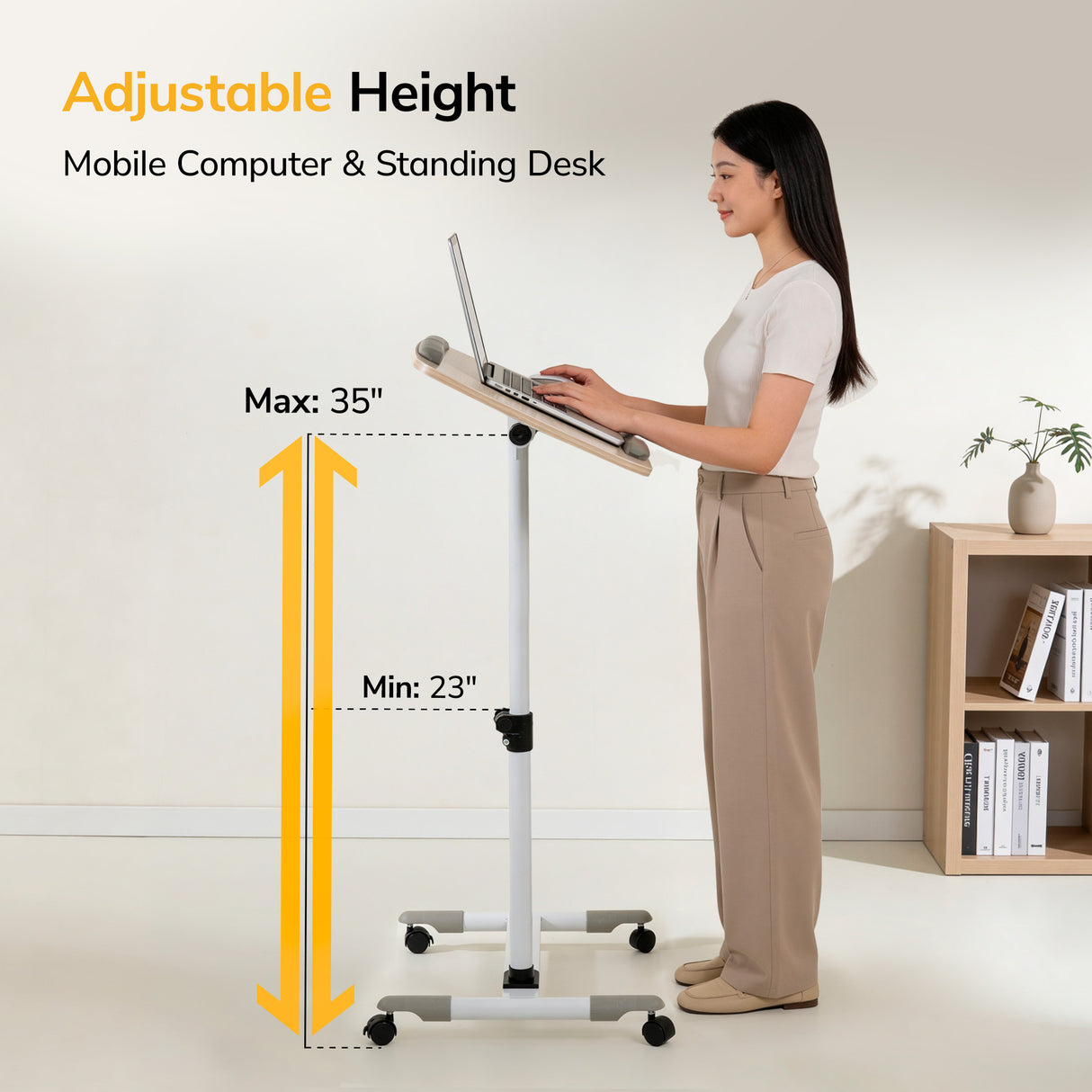 A woman types on the Mount-It! Height Adjustable Rolling Laptop Cart, which serves as a standing desk with a 23–35 inch height range. A plant and bookshelf are in the background.