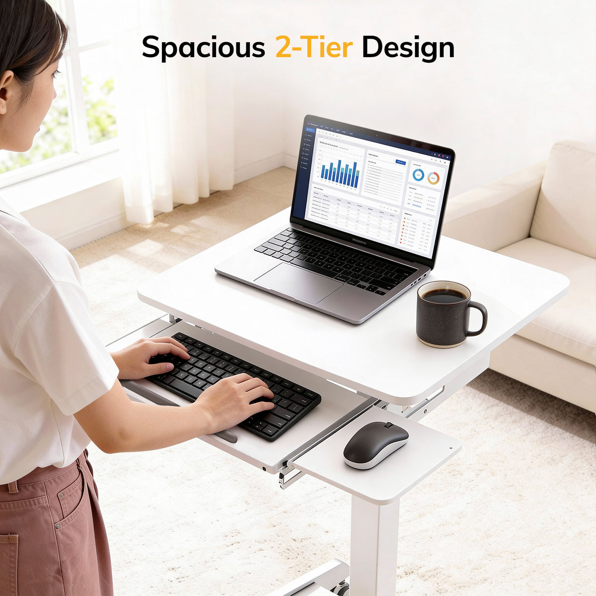 A woman uses the Mount-It! Laptop Cart with Pull-Out Keyboard Tray, a white mobile desk with a spacious 2-tier design and ergonomic tray for comfortable typing and device placement. A laptop, keyboard, mouse, and coffee mug sit on the desk.