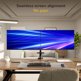 A modern office showcases the Mount-It! Dual Monitor Mount with Gas Spring Arm and Crossbar, holding two large side-by-side screens aligned seamlessly under the text: Seamless screen alignment No gaps, displaying a blue and purple light streak background.