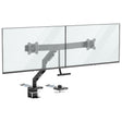 The Mount-It! Dual Monitor Mount with Gas Spring Arm and Crossbar in black securely clamps to your desk, supporting two large flat-screen monitors side by side for a tidy, adjustable dual monitor setup.