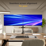 A modern office features two large monitors side by side on the Mount-It! Dual Monitor Mount with Pole and Crossbar, displaying a seamless blue and purple light streak background. Text above reads “Seamless screen alignment, No gaps.”.
