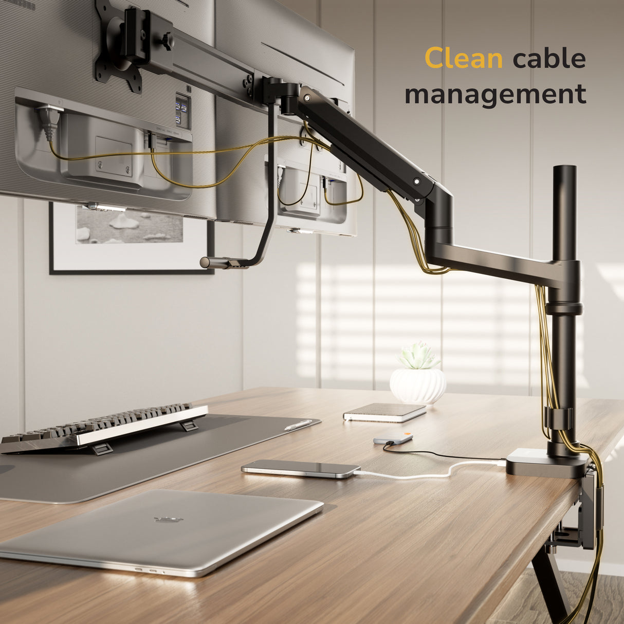 A modern workspace displays two monitors on the Mount-It! Dual Monitor Mount with Pole and Crossbar, featuring organized cables. A keyboard, mouse, laptop, and smartphone rest on a wooden desk under daylight. Text reads, “Clean cable management.”.