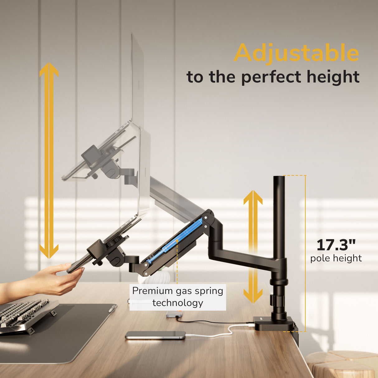 A person adjusts the Mount-It! Laptop Mount with Pole and Gas Spring Arm holding a laptop, showcasing adjustable height up to 17.3 inches. Text highlights: Adjustable to the perfect height and premium gas spring technology.