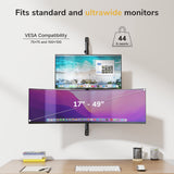 The Mount-It! Heavy-Duty Dual Stacked Monitor Wall Mount supports two 17–49" monitors (standard and ultrawide) stacked vertically above a desk. VESA compatible, holds up to 44 lbs. Books and a plant are on the desk below.