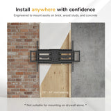 A wall-mounted TV wall mount shown installed between a brick wall, wood paneling, and concrete wall, with marketing text above and below about mounting options and stud spacing.
