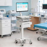 The Mount-It! MedHub Swivel Monitor Mount, a mobile medical computer cart with monitor, keyboard, drawer, and storage, is shown in a hospital room with medical equipment, cabinets, and a patient bed in the background.