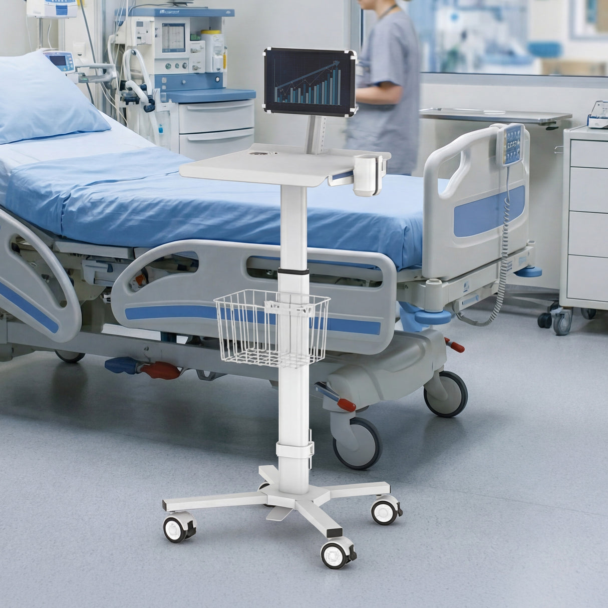 A hospital room with a bed and medical equipment features the Mount-It! MedHub Mobile Cart with Tablet Mount, cup holder, and wire basket on wheels beside the bed. In the background, a person in scrubs is walking.