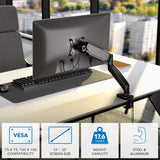 A Mount-It! Single Monitor Desk Mount with Gas Spring Arm holds a computer monitor beside a window, offering height adjustment, ergonomic design, cable management, VESA support, fits 13–32" screens up to 17.6 lb; made of steel & aluminum.