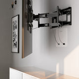 A wall-mounted TV extends on an adjustable bracket above a light wood cabinet with recessed storage. Cables are neatly routed to a Mount-It! In-Wall Media Box (Small), while a black-and-white photo hangs on the adjacent wall.