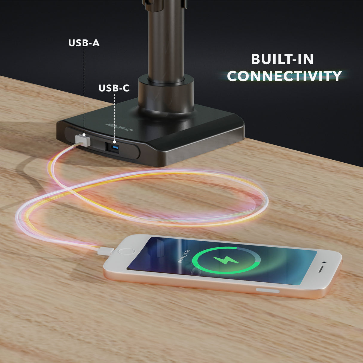 Close-up of the base of the Triple Monitor Mount with Gas Spring Arms and USB Ports showing integrated USB-A and USB-C ports charging a smartphone on a wooden desk surface, highlighting built-in connectivity and sleek black design.