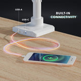 Close-up of a white triple monitor mount base with built-in USB-A and USB-C ports charging a smartphone on a wooden desk, highlighting the integrated connectivity feature of the Triple Monitor Mount with Gas Spring Arms and USB Ports for easy device charging and accessory connection.