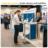 A man uses the Mount-It! Secure Universal Tablet Floor Stand with Lock at a trade show booth while a woman smiles behind the counter. Other booths and attendees are in the background. Text reads, Ideal for events, trade shows, and exhibits.