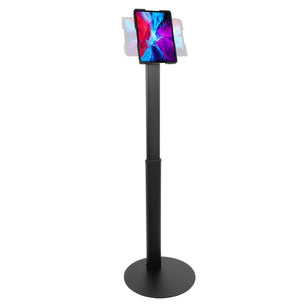 The Mount-It! Universal Tablet Floor Kiosk is a black adjustable stand that securely holds your tablet in portrait mode, with a round flat base for stability and a secure mount, shown displaying vibrant abstract graphics.