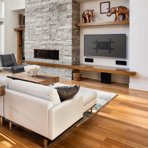 Modern living room with white sofa, stone fireplace, and a wall mounted TV.