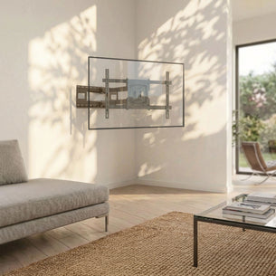 A modern living room showcases the Mount-It! Full-Motion TV Wall Mount with 40" Extension, casting leaf shadows on a white wall near a beige sofa, glass coffee table, and large windows.
