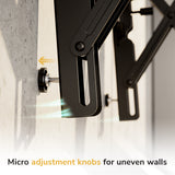 A close-up of the Mount-It! Pop-Out Video Wall Mount shows a micro adjustment knob being turned. Text reads, "Micro adjustment knobs for uneven walls," with arrows and motion lines highlighting its heavy-duty support and pop-out design.