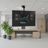 A Mount-It! Flip-Down Ceiling TV Mount secures a flat-screen monitor showing a sales growth chart in a modern office with a desk, chair, plant, and cabinets in the background.