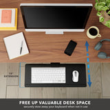 A modern desk setup with a computer monitor, notebook, pen, smartphone, coffee cup, and headphones features the Mount-It! Adjustable Keyboard Tray and Mouse Platform w/ Wrist Rest Pad sliding out 15" to free up space (indicated by blue arrows and text).