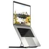 A silver laptop on the Mount-It! Portable Folding Laptop Stand is partially open and angled upward, displaying a scenic image of mountains, pine trees, and a lake.