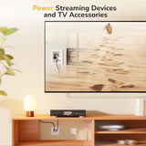 A TV mounted on the wall shows a desert scene. Below, a shelf holds a lamp and device powered by the Mount-It! In-Wall Cable Management Kit with USB, keeping cables organized. Text above says, “Power Streaming Devices and TV Accessories.”.