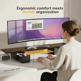 A woman uses a computer at her desk, with her screen elevated by the Mount-It! Extra Wide Monitor Riser with Drawers and Shelf for improved posture.