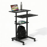 The Mount-It! Height Adjustable Rolling Stand up Desk in black features locking casters, a shelf for books, and a bottom rack for your backpack. It holds a laptop, water bottle, mouse, and keyboard for an organized and mobile workspace.