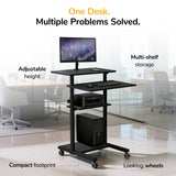 The Mount-It! Height Adjustable Rolling Stand up Desk in black features multiple shelves, locking casters, and adjustable height, holding a monitor, keyboard, mouse, printer, and computer tower in a modern office.