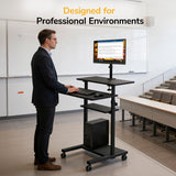 A man in business attire uses the Mount-It! Rolling Computer Work Station with Monitor Mount as a height-adjustable workstation in a modern classroom with tiered seating. Text above reads: Designed for Professional Environments.