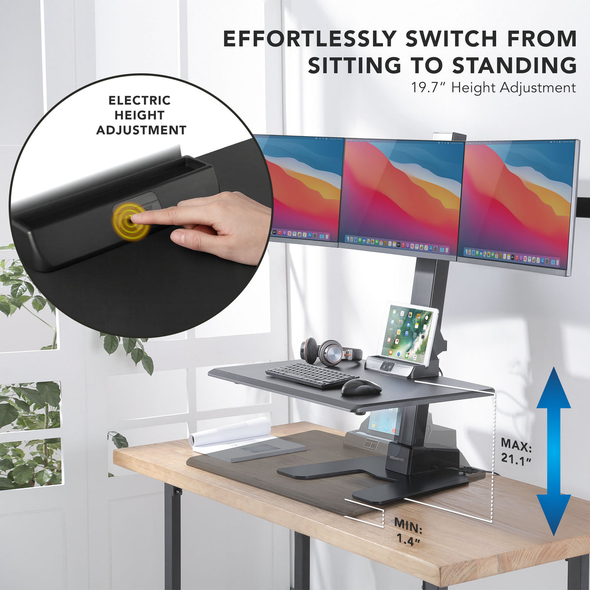 Electric height adjustable desk converter on a desk with multiple monitors and office accessories.