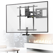 A flat-screen TV mounted on a wall above a modern fireplace, using an adjustable, extendable wall mount. A cityscape is visible through a window in the background.
